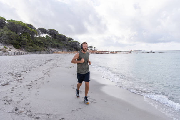 istock Man Running on Beach with Headphones 2161312896