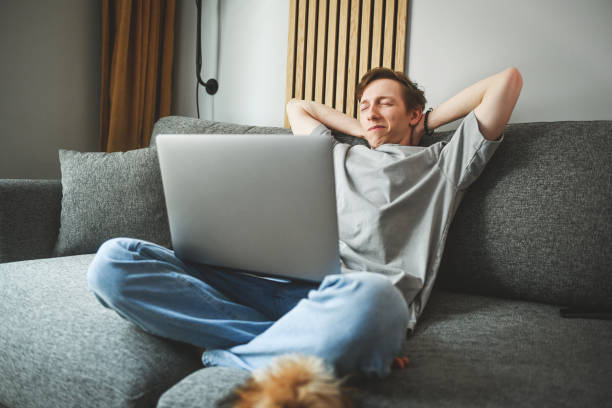 istock Teenage boy sitting on the couch using a laptop 2161313062
