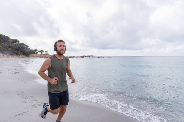 istock Man Running on Beach with Headphones 2161313251