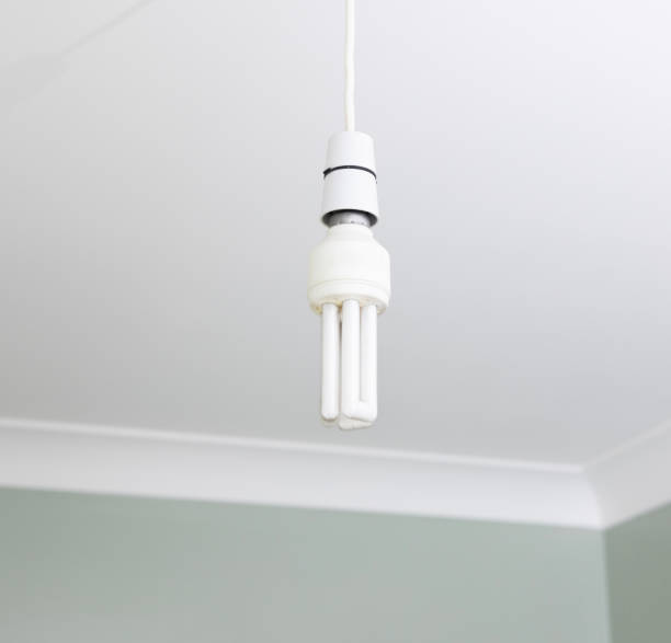 istock Energy Saving Light Bulb hanging from a domestic house ceiling 2161313736