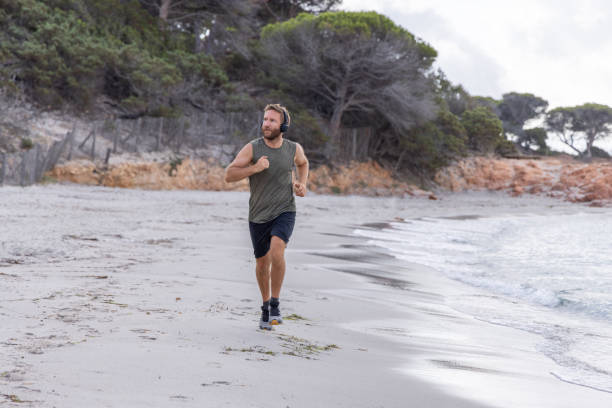 istock Man Jogging on Beach with Headphones 2161313904