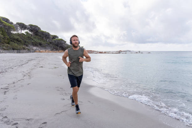 istock Sunrise Run: Man Jogging Along the Shoreline with Music 2161313918