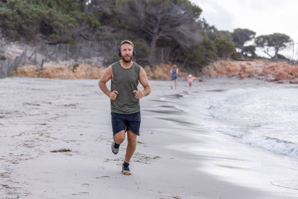 istock Man Running on Beach with Headphones 2161314257