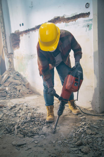 Woman with a drill machine making new flooring and wall instalations. Demolishing old first.