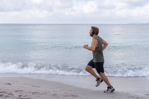 istock Solo Morning Beach Run: Man with Headphones 2161316109