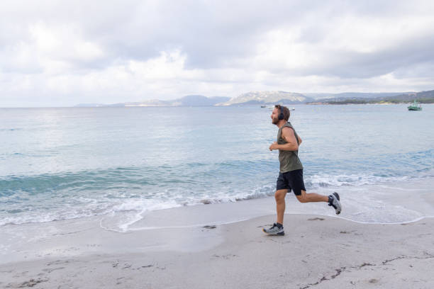 istock Man Running on Beach with Headphones 2161316115