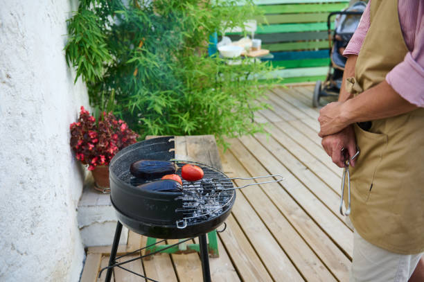Man grilling vegetables on backyard barbecue during summer day
