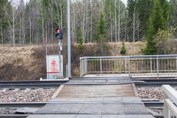 Kryuchkovo platform, Krasnoyarsk railway, Russia - May 11, 2024: Empty pedestrian crossing over railway tracks with a red semaphore signal prohibiting movement