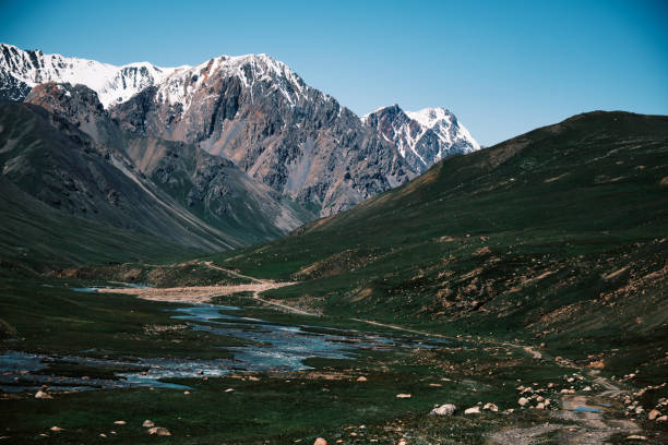 Spiked snowcapped mountain ridge above stunning mountain river valley