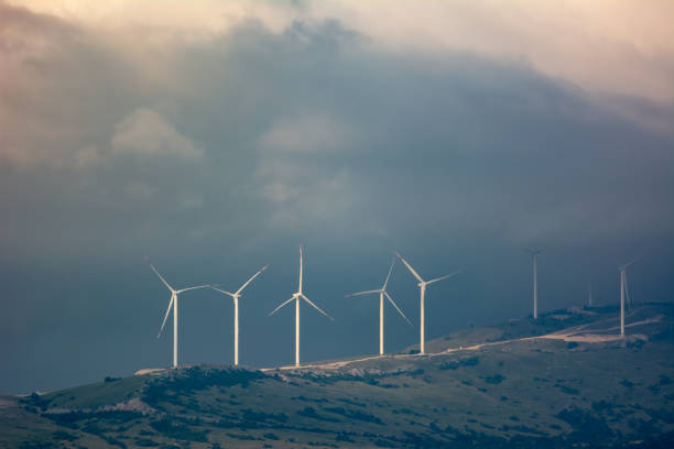 Wind park on a mountain pass illuminated by sunlight through the clouds