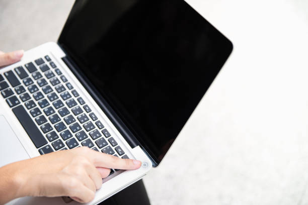 Person pressing power button on laptop.