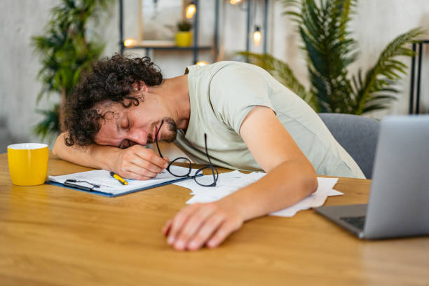 istock Mid-Adult Man Falling Asleep While Working On A Laptop On The Kitchen Table At Home 2161334527