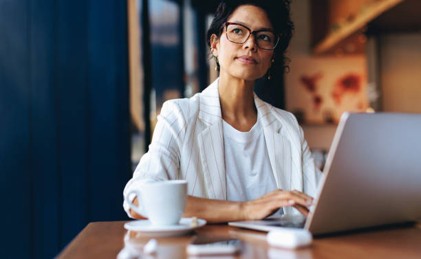 istock Professional woman working on laptop in a cafe, thinking deeply 2161336543