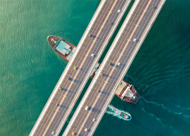 istock Cargo ship and tugboat passing under bridge 2161342845