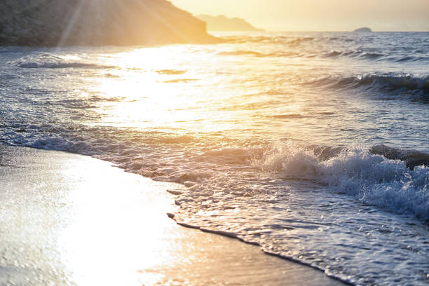 Waves breaking on a beautiful sandy beach on the shore of the mediterranean coast. Vintage stylized photo with light leaks and bokeh effect.