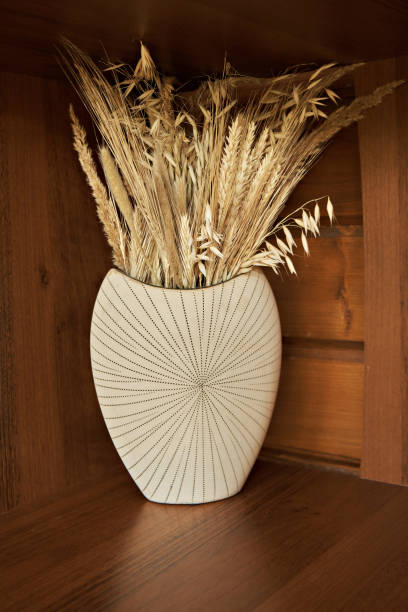 istock A creamy white vase with dry flowers on a dark background. Selective focus 2161347337