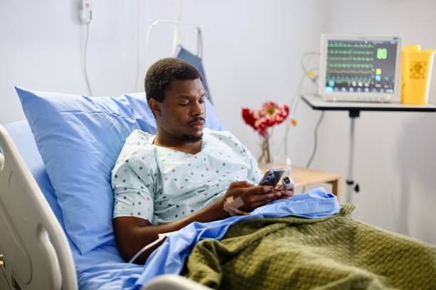 istock Young patient looking at his phone while lying at the hospital bed 2161353394
