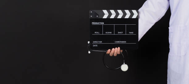 istock Doctor's hand holding stethoscope and clapper board on black background. 2161358413