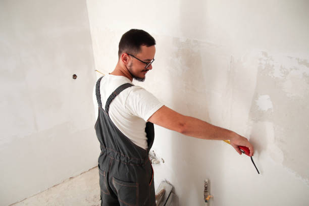 istock Construction worker measuring wall with tape measure, white background. Back view. Skilled builder using tape measure on white wall 2161359748