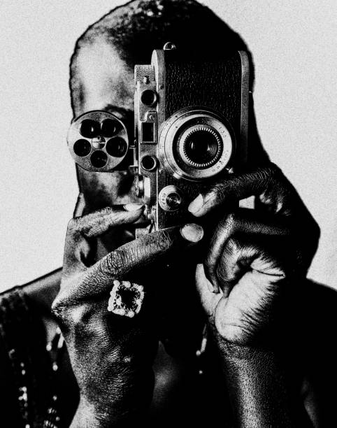 The woman with the camera. A black woman photographs frontally to the viewer with an old analog camera. Abstract and in black and white. modern art stock pictures, royalty-free photos & images