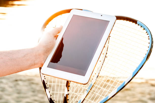 Tablet and Badminton Rackets held in hands on the beach in summer, blogger creates content on social media