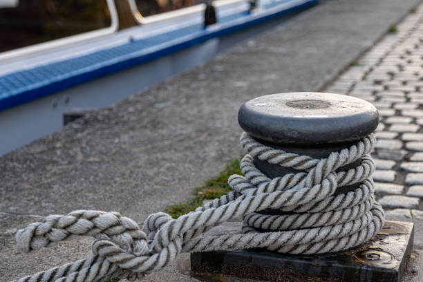 A thick white rope is wrapped around a gray metal bollard, securing a vessel to the dock.