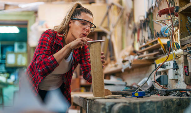 istock young female carpenter sanding wood. 2161372131