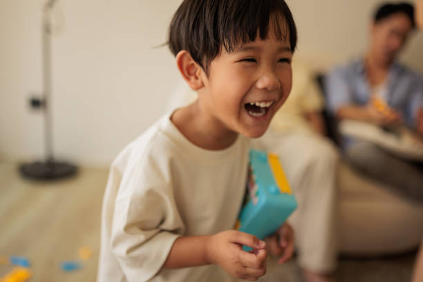 Happy little boy smiling and holding a toy in living room at home.