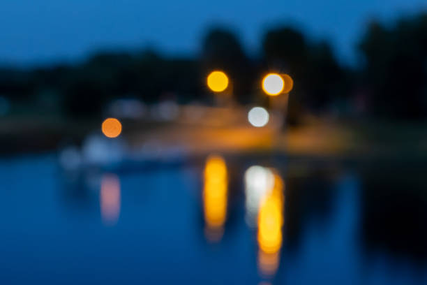 Lights from a nearby street reflect on a calm body of water at night.