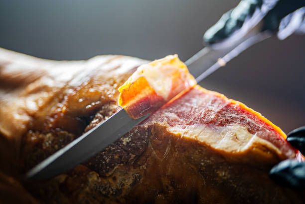 Savor the rich flavors of ham serrano tapas from Spain, artfully arranged in a row on a white plate. This delectable dish highlights the quality of Iberian ham on a wooden surface.