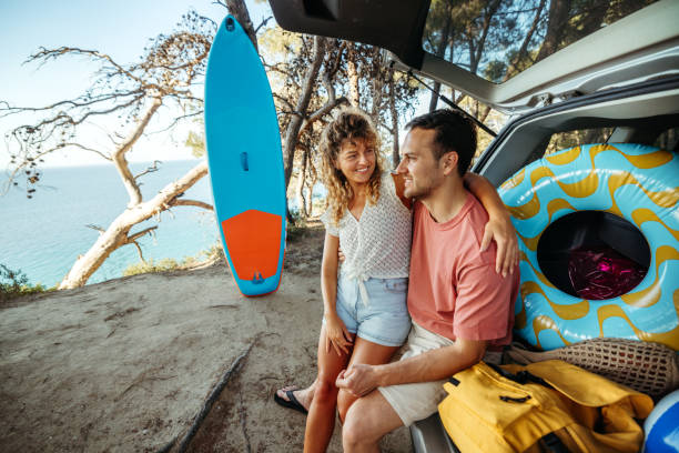 istock Young couple bonding while sitting at the car trunk 2161383903
