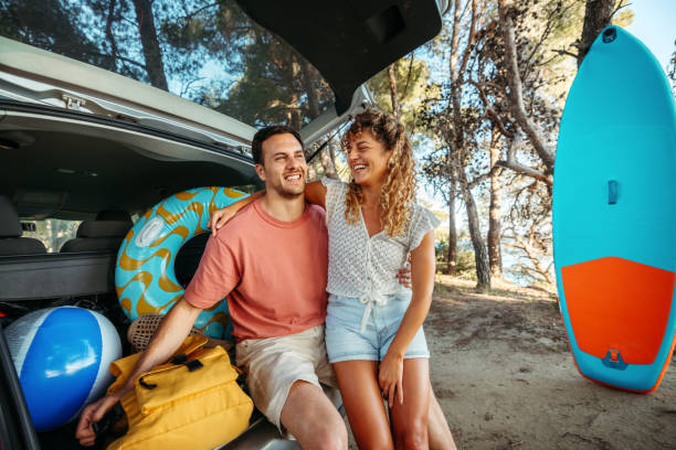 istock Young couple bonding while sitting at the car trunk 2161383904