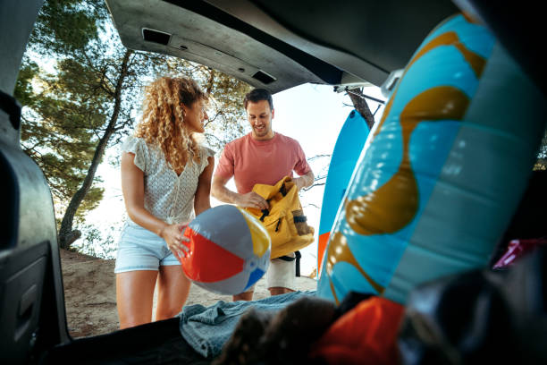 istock Young couple unpacking car trunk while getting ready for the beach adventure 2161383907