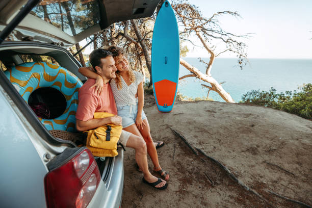 istock Young couple bonding while sitting at the car trunk 2161383908