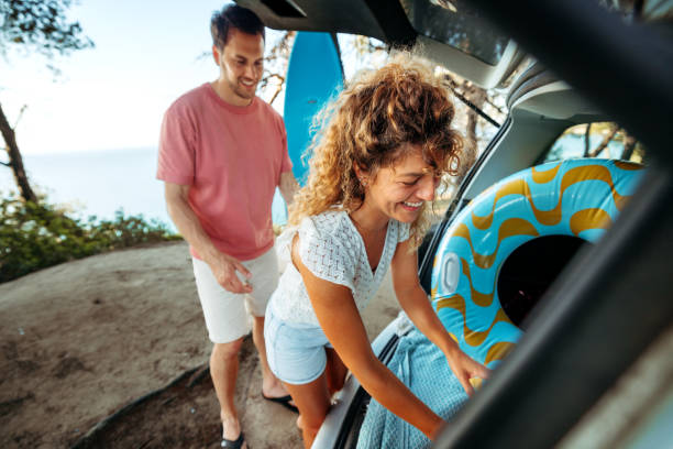 istock Young couple unpacking car trunk while getting ready for the beach adventure 2161383922