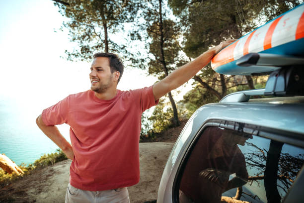 istock Young handsome man packing paddleboard on a top of his car 2161383932