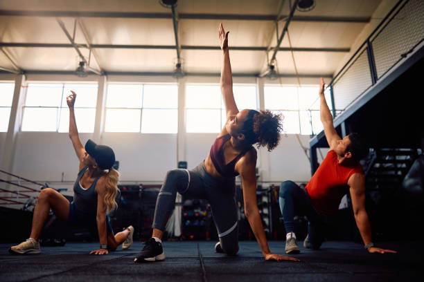 istock Group of athletes stretching while warming up during exercise class in a gym. 2161387215