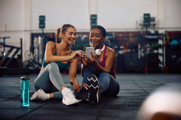 istock Athletic women using smart phone while taking break from exercising in a gym. 2161387284