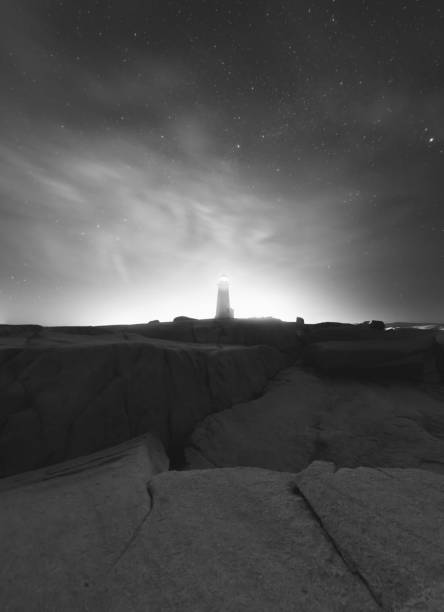 Peggy's Cove Lighthouse backlit by thin clouds overhead. Long exposure.
