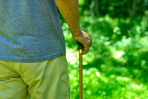 Hands of an old man walking with a cane