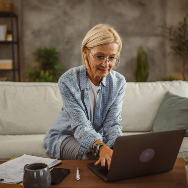 istock Mature woman work from home and compere data from laptop and clipboard 2161392653