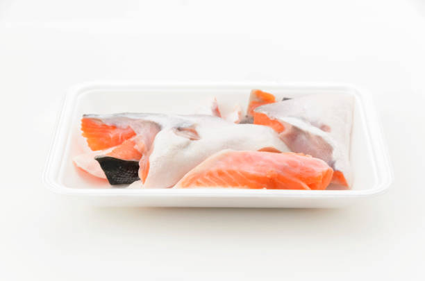 Silver salmon scraps in foam food tray on white background.