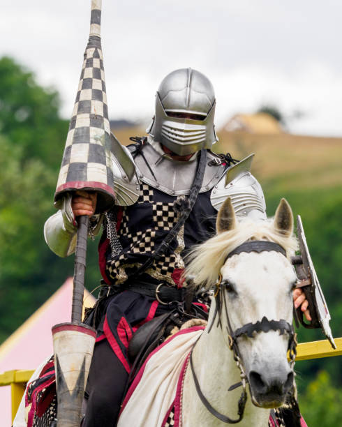 Linlithgow, Scotland - 30th Jun 2024: Mounted man garbed as a medieval knight during a reenactment event at Linlithgow Palace, Scotland.  During the event, people dressed as knights and other medieval characters perform jousts on horseback and battle using replica weapons and armour, and demonstrate various skills and work based on medieval techniques.Such events are a popular attraction for both tourists and locals during the summer season.