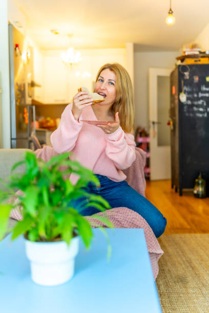 istock Woman biting a healthy sandwich sitting on the sofa 2161396854
