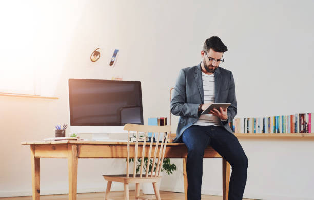 istock Remote work, man and tablet at desk for creativity, contact or research articles for book review. Male writer, home office or technology at table for update, information or communication for feedback 2161397774