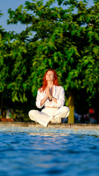 istock A young beautiful red-haired woman meditating by the poolside 2161397953