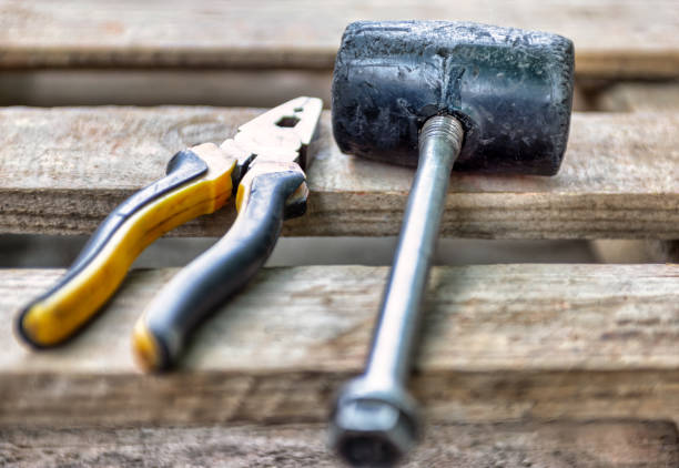 used tools , rubber hammer and pliers on wooden planks