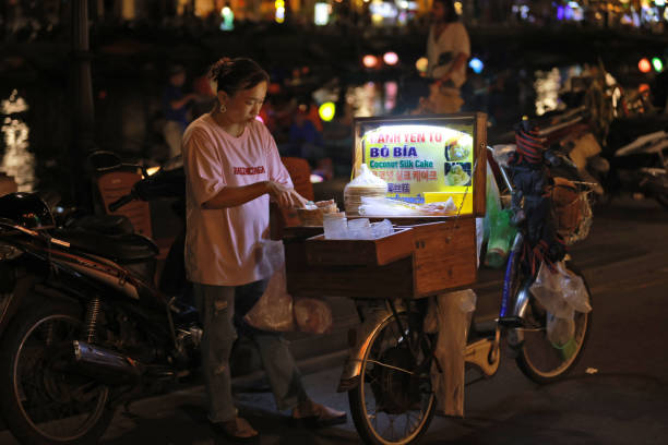 Ho Chi Minh City, Vietnam - March 16, 2025: Traditional street fast food mobile cart with elderly poor vendor, Asian city charm, unsanitary condition