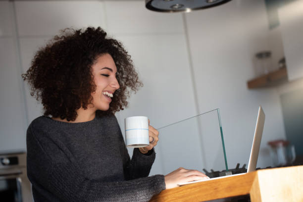 istock Young woman drinking coffee and working from home in modern kitc 2161403671