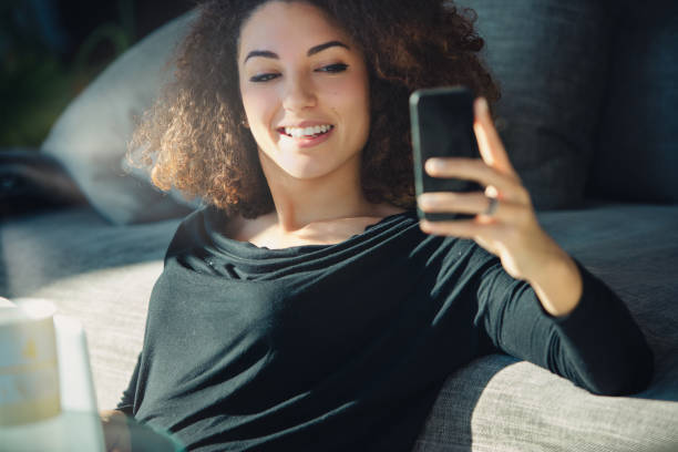 istock Young woman relaxing on couch using smartphone at home 2161404296